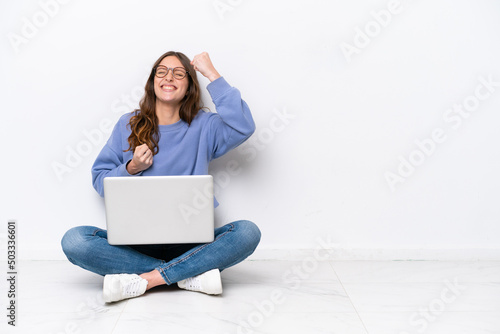 Fotografia Young caucasian woman with a laptop sitting on the floor isolated on white backg