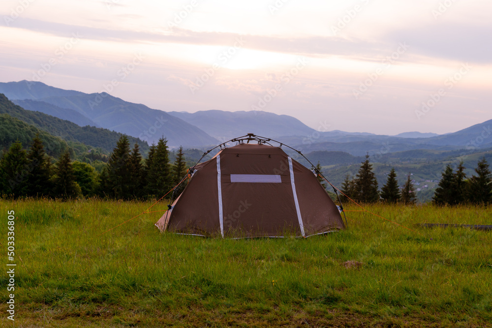 Brown tent. Quick installation system. Summer day. Mountains and forest, travel and tourism concept. Camping.