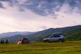 A brown tent and an old car with a trunk on the roof. Quick installation system. Summer day. Mountains and forest, travel and tourism concept. Camping.