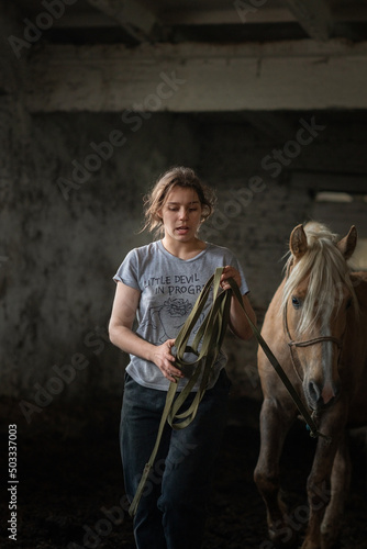 A young beautiful female worker takes care of a horse on a farm.