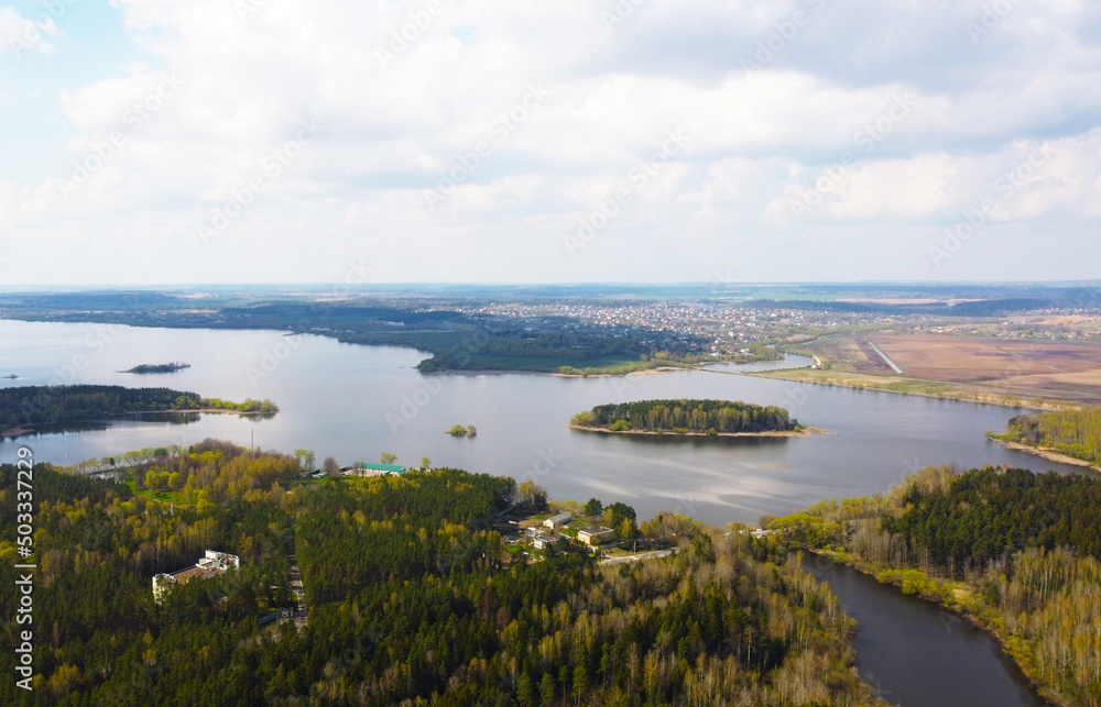 Top view from a quadrocopter of a spring green forest over a lake