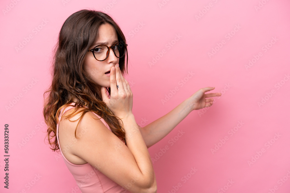 Young caucasian woman isolated on pink background with surprise expression while pointing side Young caucasian woman isolated on pink background with surprise expression while pointing side