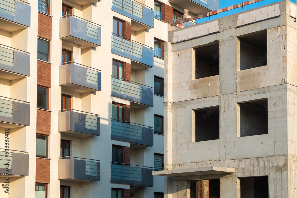 Building under construction next to modern residential building on a sunny day