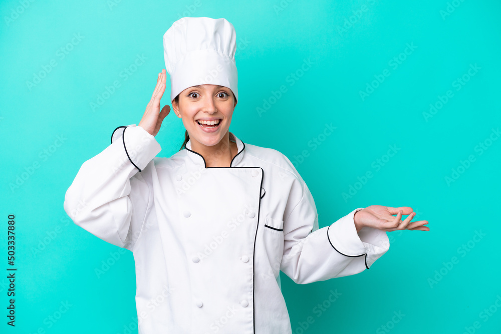 Young caucasian chef woman isolated on blue background surprised and pointing finger to the side Young caucasian chef woman isolated on blue background surprised and pointing finger to the side