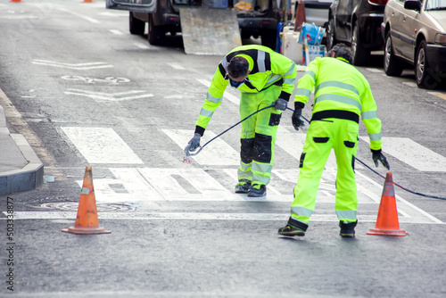 Traffic line painting. Workers painting white street lines on pedestrian crossing