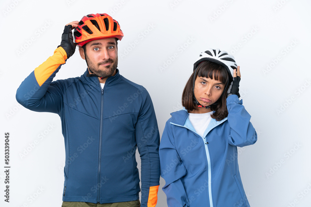 Young cyclist couple isolated on white background with an expression of frustration and not understanding Young cyclist couple isolated on white background with an expression of frustration and not understanding