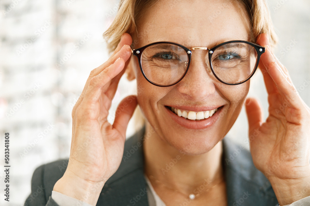 Smiling woman in glasses in front of showcase in an optics store Smiling woman in glasses in front of showcase in an optics store