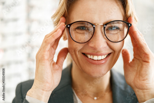 Konstfotografi Smiling woman in glasses in front of showcase in an optics store