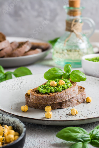 Appetizing bruschetta made from rye bread, pesto and chickpeas on a plate. Vertical view