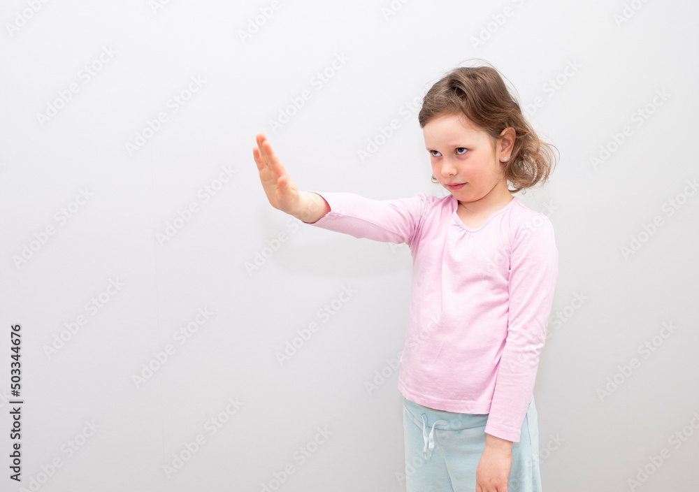 Child, Caucasian 6 years old, in a pink coat on a gray background. The child is stressed, shows a stop gesture with his hands, he is not happy. Child, Caucasian 6 years old, in a pink coat on a gray background. The child is stressed, shows a stop gesture with his hands, he is not happy.