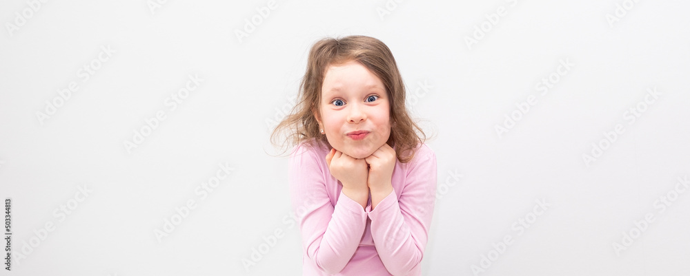 A Caucasian girl, 6 years old, in a pink T-shirt on a gray background. The child is happy and smiles and looks into the camera, emotions on his face. A Caucasian girl, 6 years old, in a pink T-shirt on a gray background. The child is happy and smiles and looks into the camera, emotions on his face.