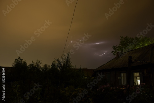 Thunderbolt (Lightning) over the house and dark stormy sky on the background