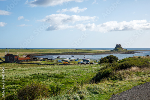 Lindisfarne/England: 10th Sept 2019: Holy Island Castle view from coastline with tide in blue sky