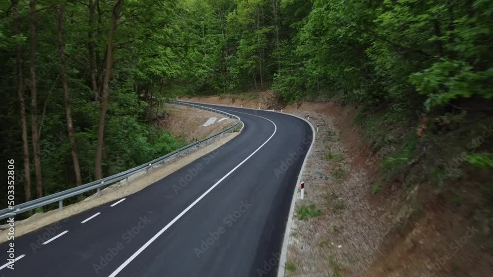 Aerial shot of a winding road passing through a dense green forest Aerial shot of a winding road passing through a dense green forest