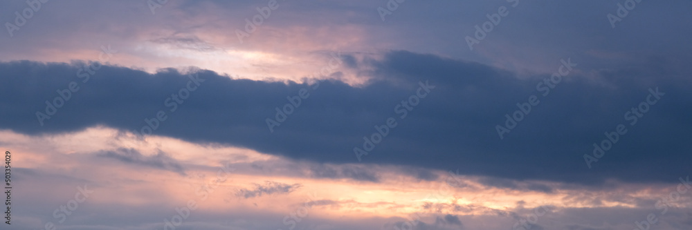 Beautiful dramatic evening sky in blue, yellow and orange colors. Sunset sky. Long banner