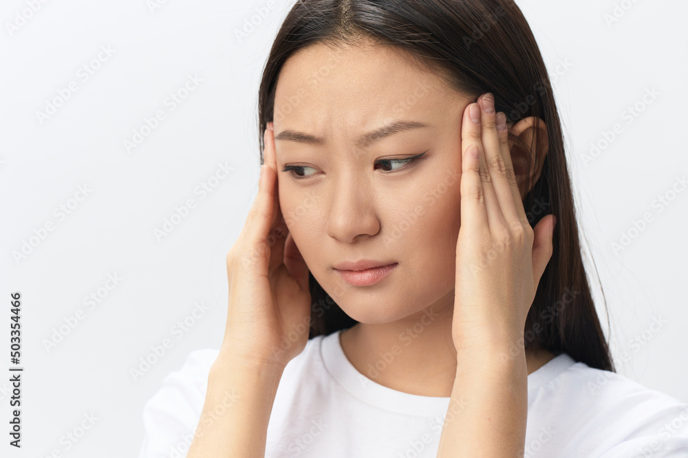Migraine. Side view of unhappy suffering from headache tanned beautiful young Asian woman touching forehead posing isolated on white background. Injuries Poor health Illness concept. Cool offer Banner Migraine. Side view of unhappy suffering from headache tanned beautiful young Asian woman touching forehead posing isolated on white background. Injuries Poor health Illness concept. Cool offer Banner