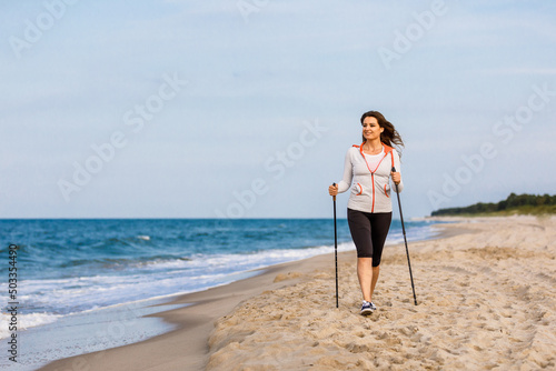 Nordic walking - young woman training at seaside 
