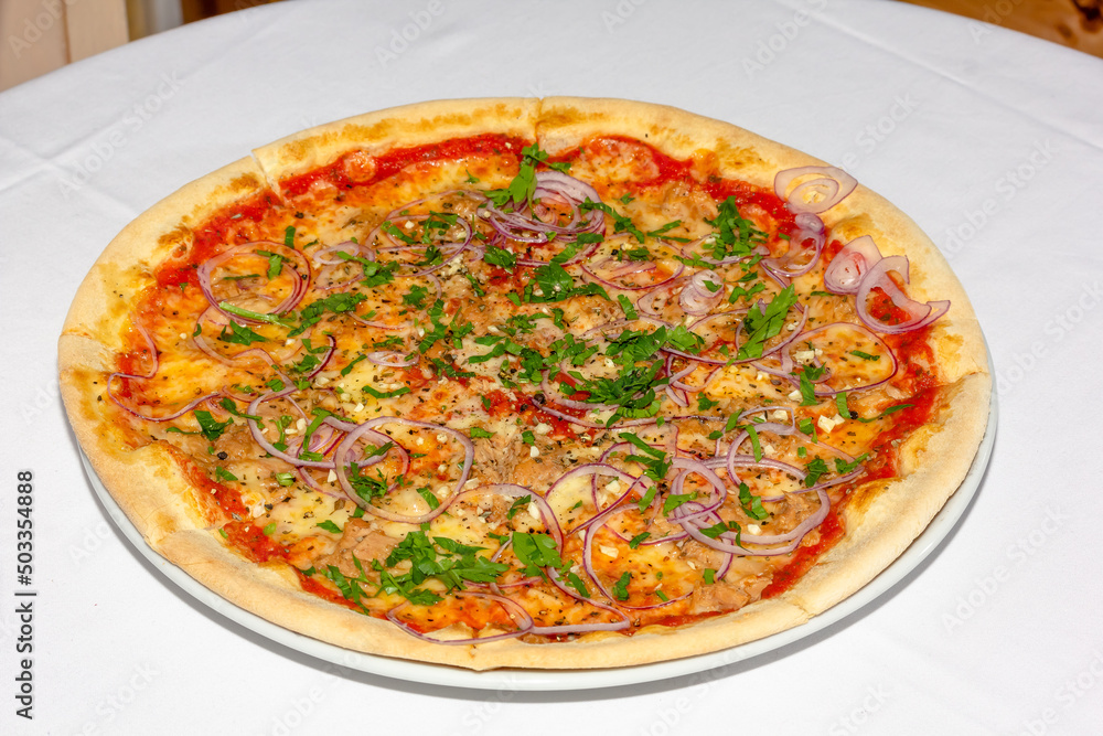Delicious pizza with tuna, pickled onions, cheese and tomato sauce. Isolated on white.