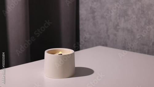 Candle soy homemade in ceramic burning in grey modern interior room, atmosphere and minimalistic composition 