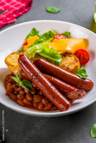 English Breakfast on a white plate, sausage,beans,bread,cheese and vegetables, side view on grey table vertical