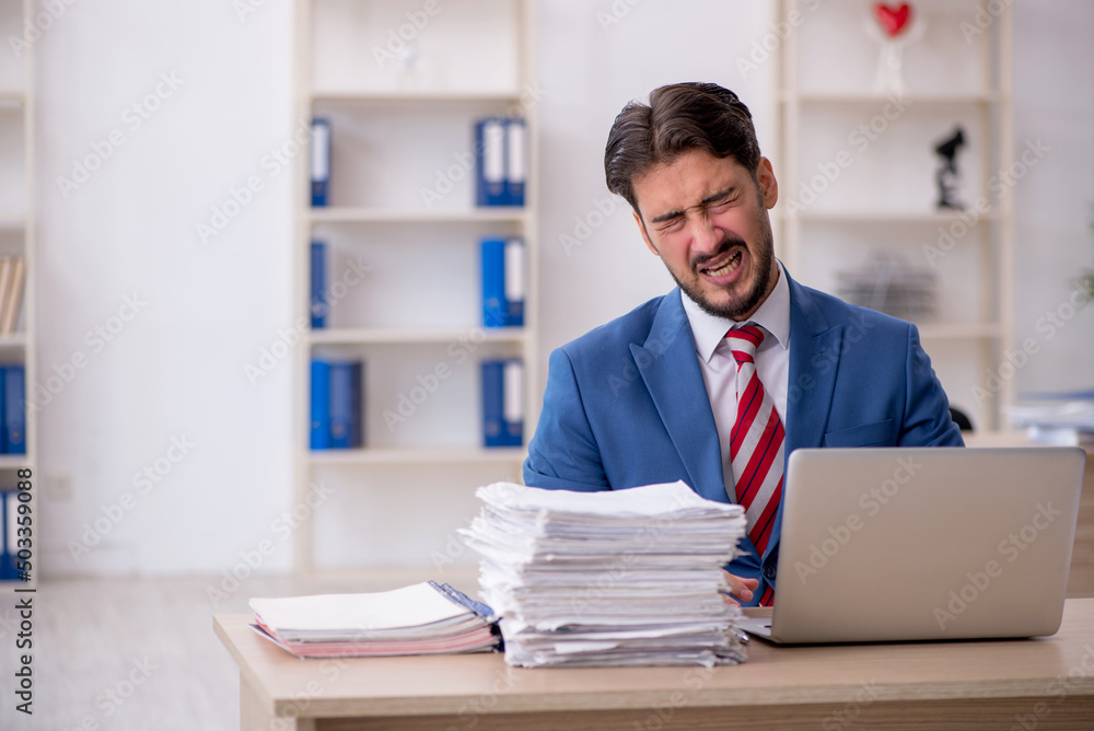 Young male employee and too much work in the office Young male employee and too much work in the office