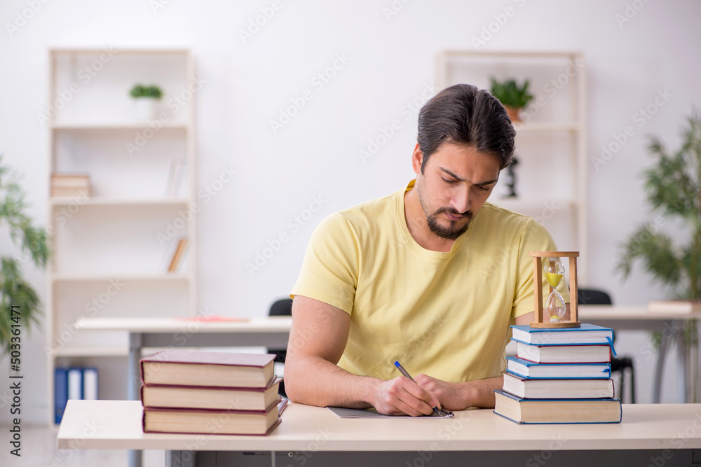 Young male student preparing for exams in time management concep Young male student preparing for exams in time management concep