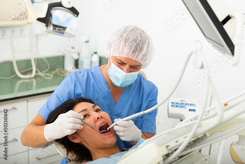 Man doctor treats patient teeth using boron machine in dental clinic