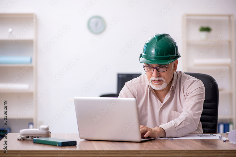 Old male architect working in the office Old male architect working in the office
