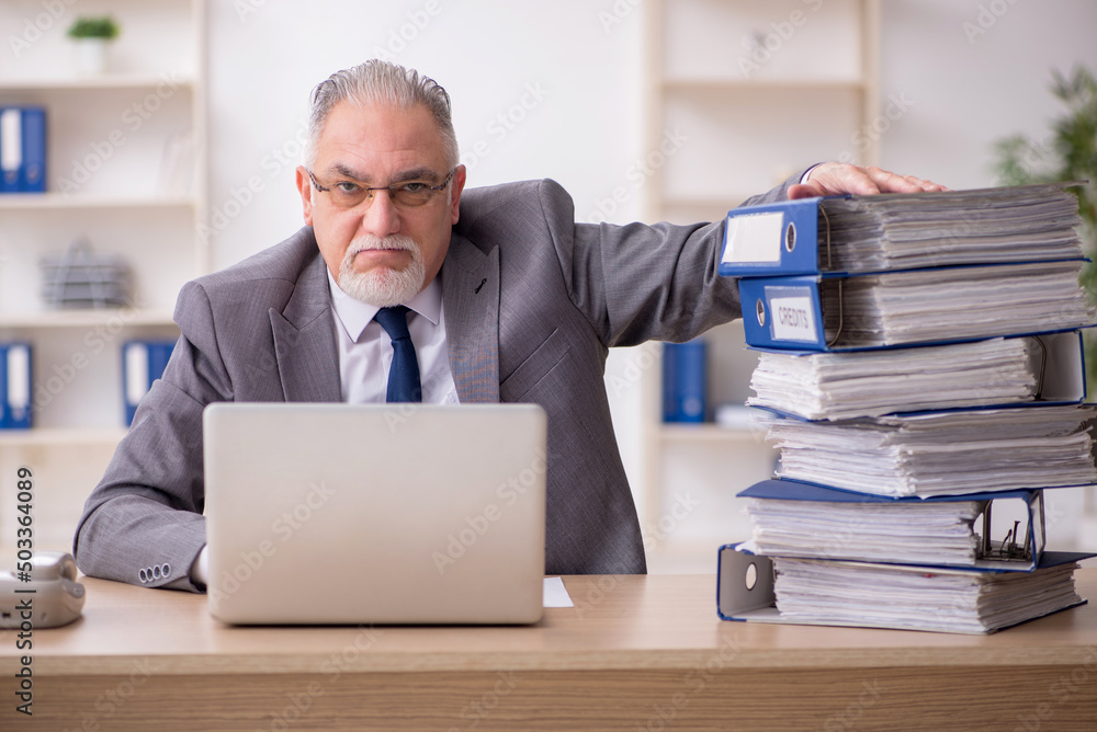 Old male employee unhappy with excessive work in the office Old male employee unhappy with excessive work in the office