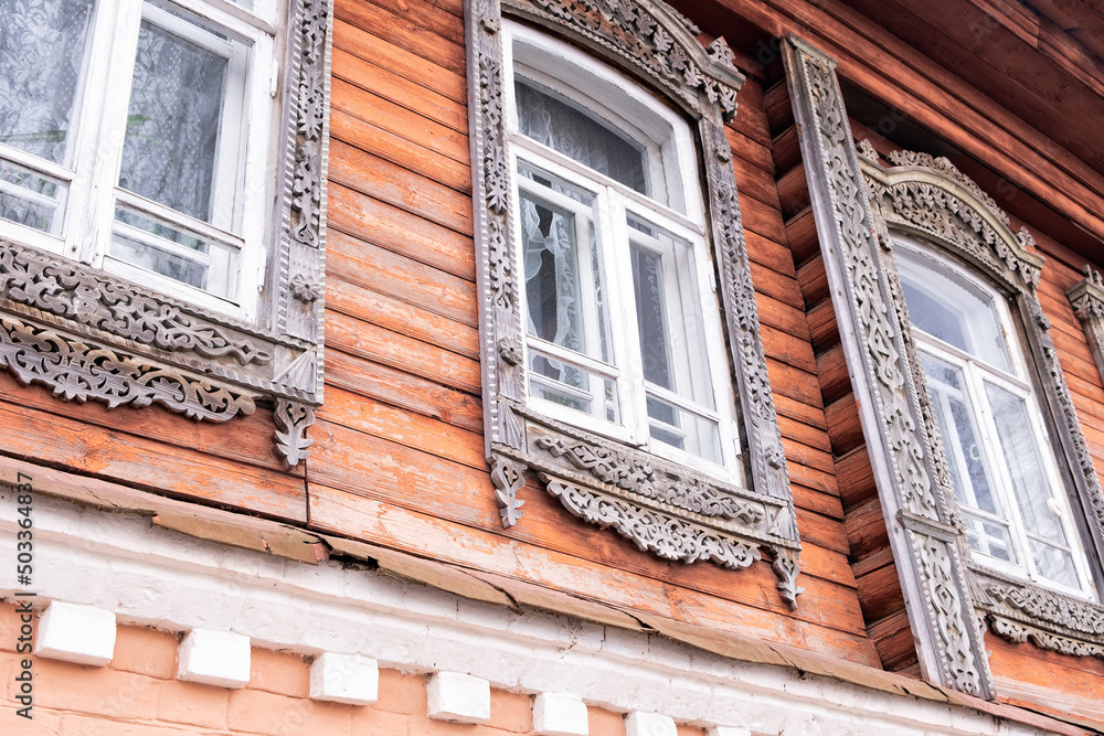 Obraz premium Beautiful old windows. An architectural monument. Old Russian style. Wooden architecture. An old carved frame. Architectural decorative element.
