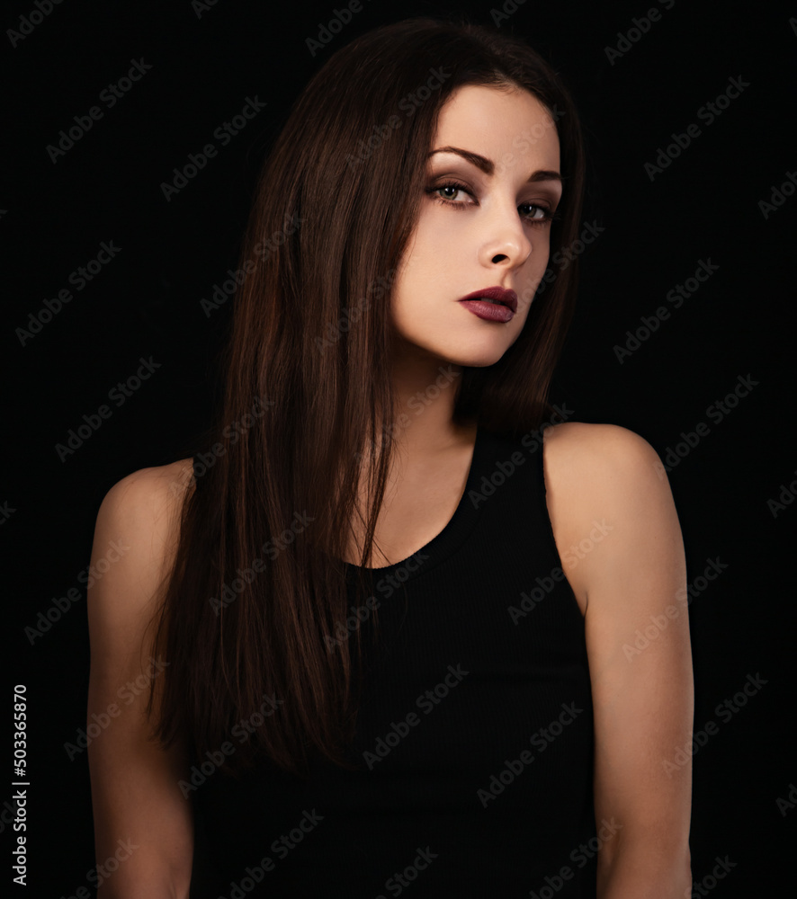 Beautiful bright makeup woman with red lipstick in black top and long brown healthy hair looking on dark black shadow background. Closeup Beautiful bright makeup woman with red lipstick in black top and long brown healthy hair looking on dark black shadow background. Closeup