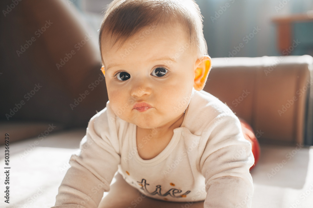 Caucasian baby lying on stomach with serious face looking at camera. Family care. Baby care. Caucasian baby lying on stomach with serious face looking at camera. Family care. Baby care.