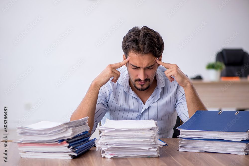 Young male employee and too much work in the office Young male employee and too much work in the office