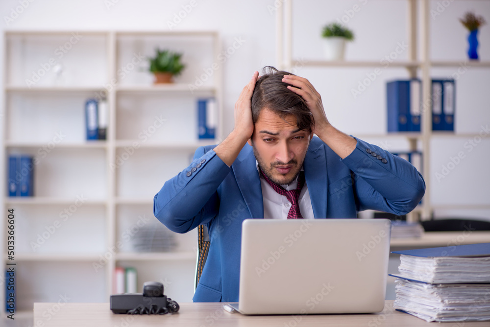 Young male employee and too much work in the office Young male employee and too much work in the office