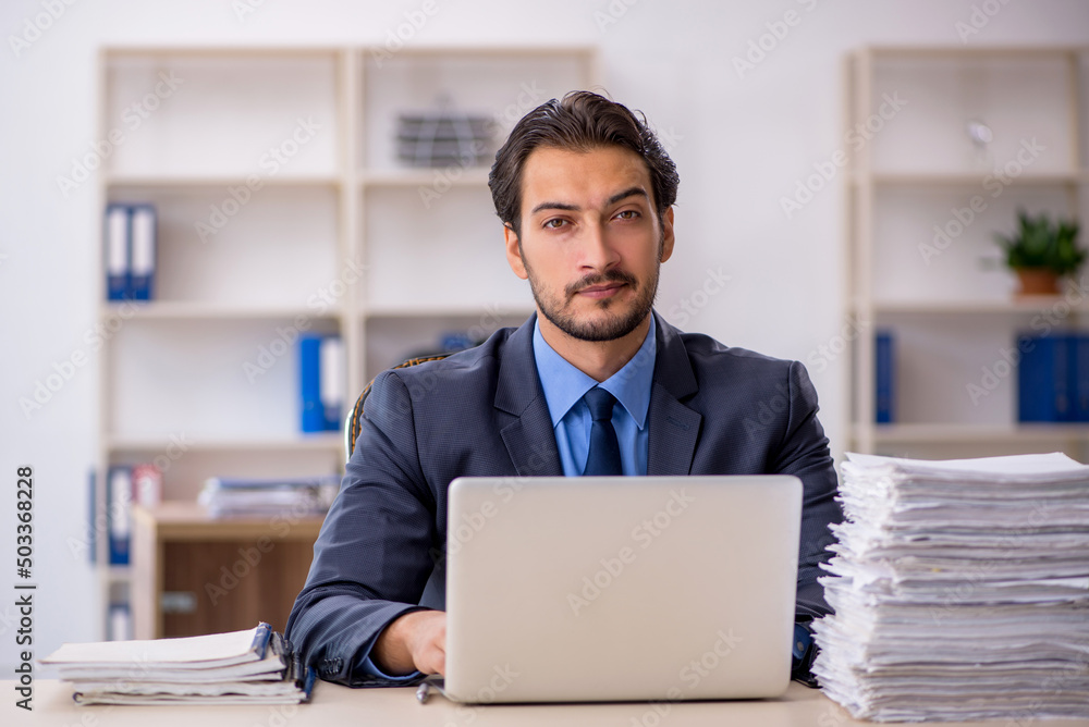 Young male employee and too much work in the office Young male employee and too much work in the office