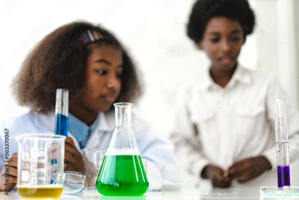 Two african american cute little boy and girl student child learn science research and doing a chemical science experiment making analyzing and mix liquid in test tube on class at school Two african american cute little boy and girl student child learn science research and doing a chemical science experiment making analyzing and mix liquid in test tube on class at school