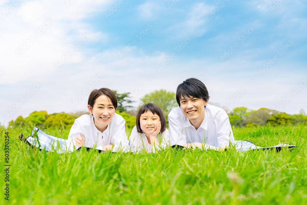 草原に寝転ぶ親子　ファミリー　子育て　ピクニック