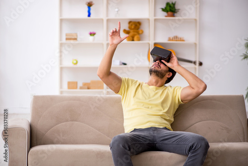 Young man wearing virtual glasses at home