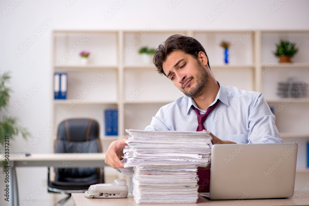 Obraz premium Young male employee and too much work in the office