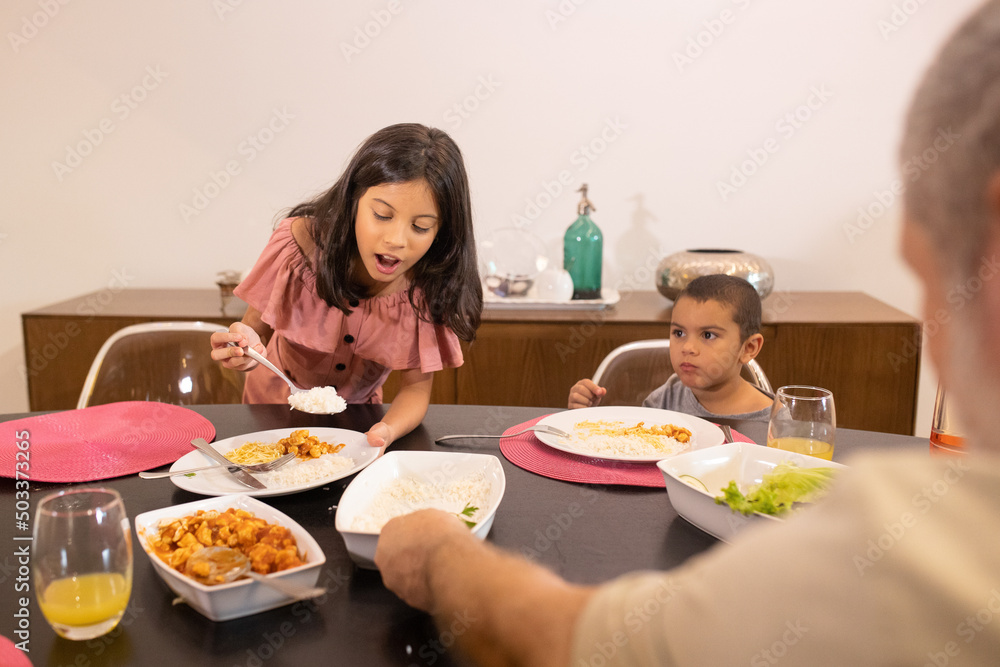 Jantar familiar. Menina servindo o prato do irmão e o vovô ajuda Jantar familiar. Menina servindo o prato do irmão e o vovô ajuda