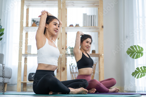 Asian active woman friend doing Yoga Pilates workout together at home.  © Kawee