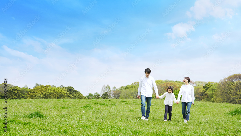 青空の草原を歩く家族　環境　子育て