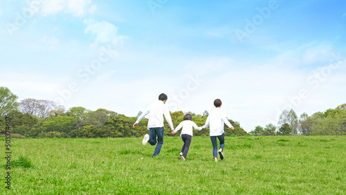 青空の草原を走る家族　環境　子育て © metamorworks