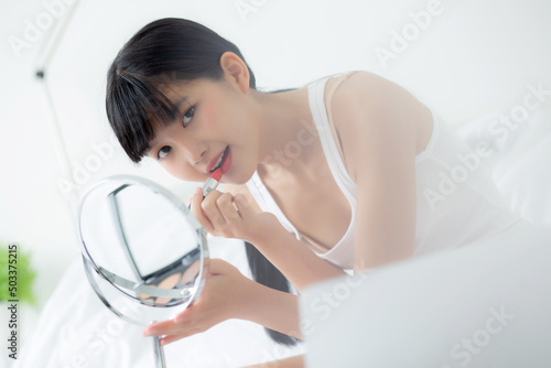 Beautiful young asian woman applying lipstick red on mouth, beauty girl looking facial at mirror for makeup cosmetic with lips elegance, make up with sexy of female, skin care and health concept.
