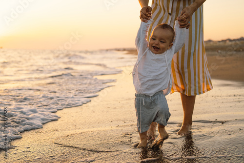 happy mother's day. Beautiful mother and baby play on the beach. Mum and her Child together enjoying sunset. Loving single mother hugs cute little son.