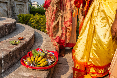 Colourfully dressed newly married Indian woman, religiusly offering fruits on the stair case of Hindu temple. photo
