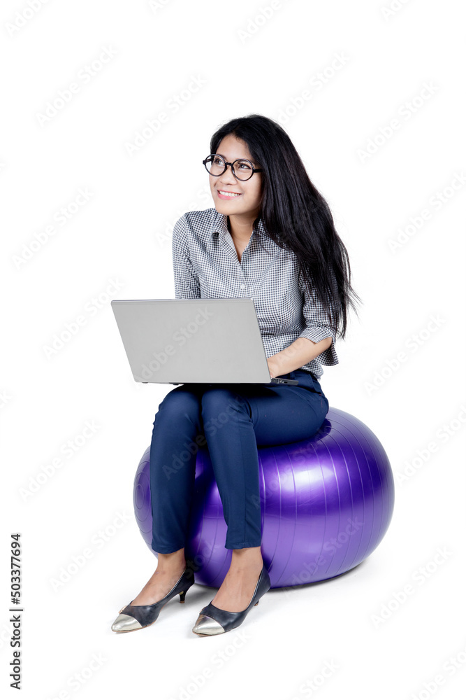 Young businesswoman using a laptop on yoga ball Young businesswoman using a laptop on yoga ball