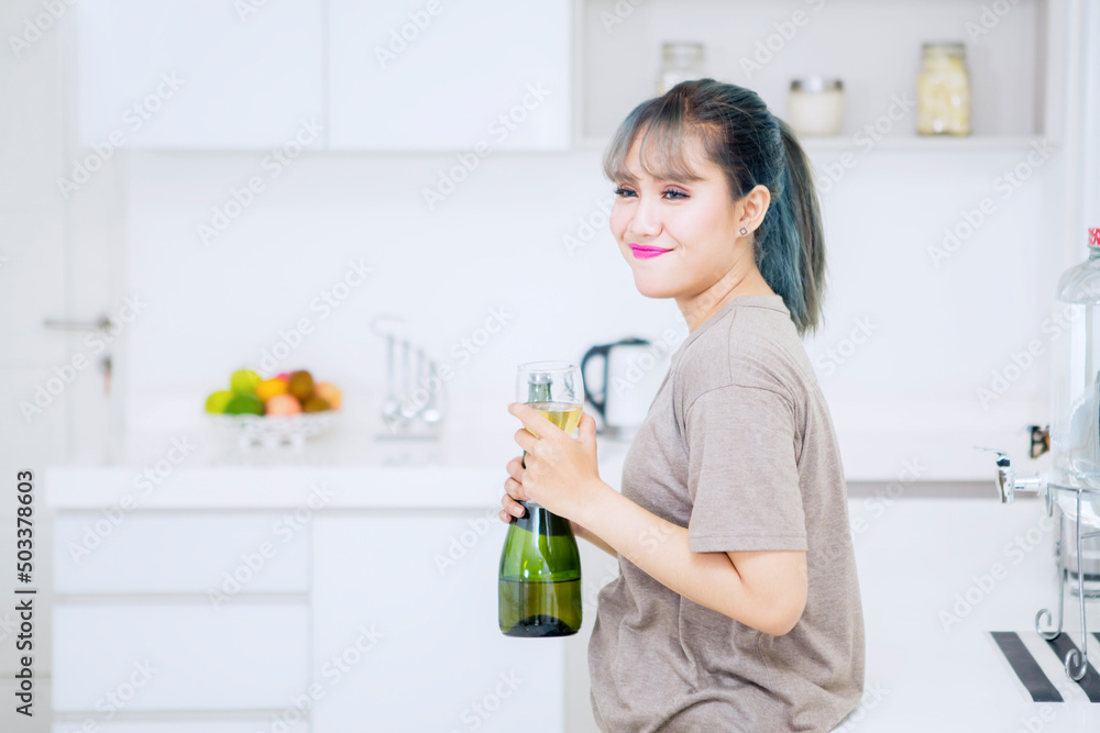 Happy woman enjoying wine drink in kitchen Happy woman enjoying wine drink in kitchen