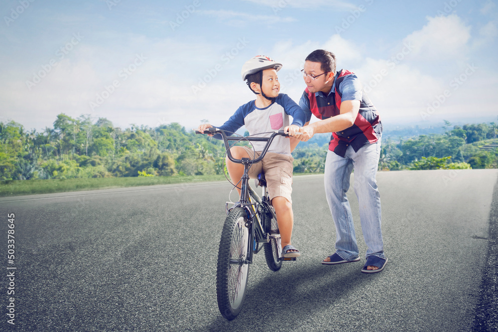 Little boy learning to ride a bicycle with father Little boy learning to ride a bicycle with father