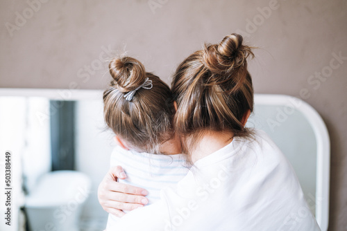 Young mother woman with long hair with little tween girl daughter in pajamas having fun in the morning at home, family spending time together in bathroom